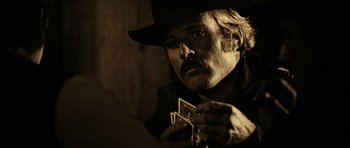 Movie still from “Butch Cassidy and the Sundance Kid” (1969), directed by George Roy Hill – A man in a black hat holding two playing cards; Close Up shot, Over the shoulder angle