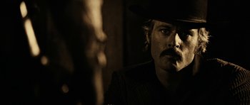 Movie still from “Butch Cassidy and the Sundance Kid” (1969), directed by George Roy Hill – A man in a cowboy hat is smoking a cigarette; Close Up shot, Over the shoulder angle