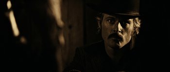 Movie still from “Butch Cassidy and the Sundance Kid” (1969), directed by George Roy Hill – A man in a cowboy hat is smoking a cigarette; Close Up shot, Over the shoulder angle