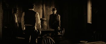 Movie still from “Butch Cassidy and the Sundance Kid” (1969), directed by George Roy Hill – A man wearing a hat standing next to a table; Medium shot, Over the shoulder angle