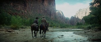 Movie still from “Butch Cassidy and the Sundance Kid” (1969), directed by George Roy Hill – Two men on horses in the middle of a river; Extreme Wide shot, Low angle