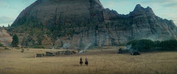 Movie still from “Butch Cassidy and the Sundance Kid” (1969), directed by George Roy Hill – Two people are standing in the middle of a field near a mountain; Extreme Wide shot, Low angle
