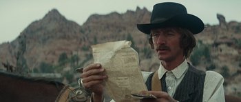 Movie still from “Butch Cassidy and the Sundance Kid” (1969), directed by George Roy Hill – A man in a cowboy hat holding an old newspaper; Close Up shot, Over the shoulder angle