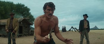 Movie still from “Butch Cassidy and the Sundance Kid” (1969), directed by George Roy Hill – A shirtless man holding a knife and a banana; Medium shot, Low angle