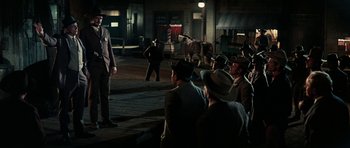 Movie still from “Butch Cassidy and the Sundance Kid” (1969), directed by George Roy Hill – A group of men in suits and hats on a street; Wide shot, Over the shoulder angle