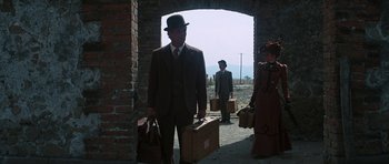 Movie still from “Butch Cassidy and the Sundance Kid” (1969), directed by George Roy Hill – A man in a suit and a bowler hat carrying suitcases while standing next to a woman; Wide shot, Low angle