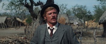 Movie still from “Butch Cassidy and the Sundance Kid” (1969), directed by George Roy Hill – A man in a suit and a hat is standing in front of a tree; Close Up shot, Low angle