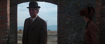 Movie still from “Butch Cassidy and the Sundance Kid” (1969), directed by George Roy Hill – A man in a suit and hat standing in front of a brick wall; Medium shot, Low angle