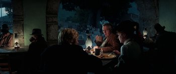 Movie still from “Butch Cassidy and the Sundance Kid” (1969), directed by George Roy Hill – A group of people sitting at a table with food; Medium shot, Over the shoulder angle