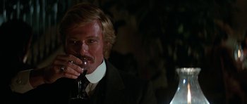 Movie still from “Butch Cassidy and the Sundance Kid” (1969), directed by George Roy Hill – A man in a suit and tie drinking a glass of wine; Close Up shot, Over the shoulder angle