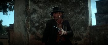 Movie still from “Butch Cassidy and the Sundance Kid” (1969), directed by George Roy Hill – A man with a hat and a gun in his hand; Medium shot, Low angle