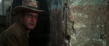 Movie still from “Butch Cassidy and the Sundance Kid” (1969), directed by George Roy Hill – A man wearing a hat standing next to a wall; Close Up shot, Low angle