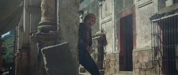 Movie still from “Butch Cassidy and the Sundance Kid” (1969), directed by George Roy Hill – A man leaning against a wall in an alley; Medium shot, Low angle