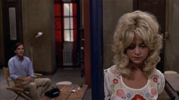 Movie still from “Butterflies Are Free” (1972), directed by Milton Katselas – A woman with blonde curly hair and a white dress; Medium shot, Over the shoulder angle