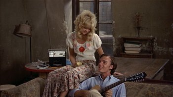 Movie still from “Butterflies Are Free” (1972), directed by Milton Katselas – A man and a woman sitting on the floor playing a guitar; Medium shot, High angle