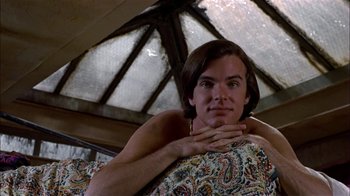 Movie still from “Butterflies Are Free” (1972), directed by Milton Katselas – A man sitting on top of a couch with his hands on his chest; Close Up shot, Low angle