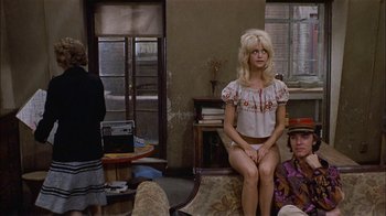 Movie still from “Butterflies Are Free” (1972), directed by Milton Katselas – A woman sitting on top of a couch in a room; Wide shot, Over the shoulder angle