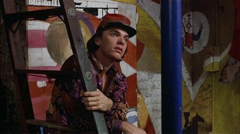 Movie still from “Butterflies Are Free” (1972), directed by Milton Katselas – A man holding a ladder in front of a painting; Medium shot, Low angle