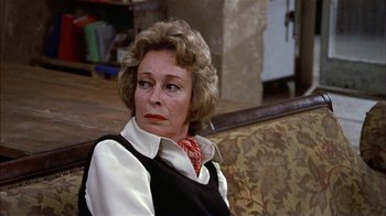 Movie still from “Butterflies Are Free” (1972), directed by Milton Katselas – An older woman sitting on a couch in a living room; Close Up shot, Over the shoulder angle