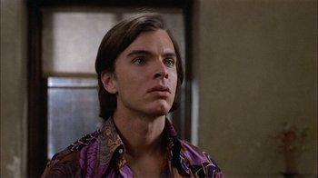 Movie still from “Butterflies Are Free” (1972), directed by Milton Katselas – A man with long brown hair wearing a purple shirt; Close Up shot, Low angle