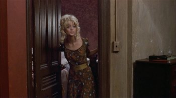 Movie still from “Butterflies Are Free” (1972), directed by Milton Katselas – A woman standing in front of a door wearing a dress; Medium shot, High angle