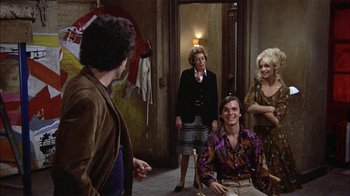 Movie still from “Butterflies Are Free” (1972), directed by Milton Katselas – A group of people standing in a room; Wide shot, Over the shoulder angle