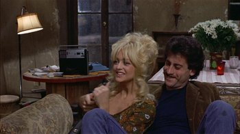 Movie still from “Butterflies Are Free” (1972), directed by Milton Katselas – A woman sitting next to a man on a couch in a room; Medium shot, High angle