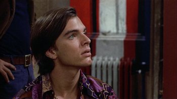 Movie still from “Butterflies Are Free” (1972), directed by Milton Katselas – A man with long brown hair wearing a purple shirt looking up; Close Up shot, Low angle