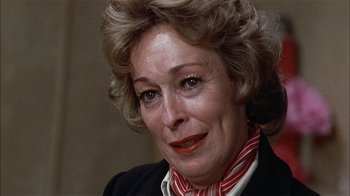 Movie still from “Butterflies Are Free” (1972), directed by Milton Katselas – An older woman wearing a black jacket and a red and white striped neck tie; Close Up shot, Over the shoulder angle
