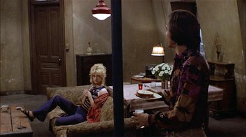 Movie still from “Butterflies Are Free” (1972), directed by Milton Katselas – Two people sitting on a couch in a living room; Wide shot, High angle