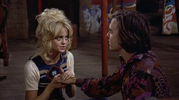 Movie still from “Butterflies Are Free” (1972), directed by Milton Katselas – A man and a woman sitting on the ground; Medium shot, High angle