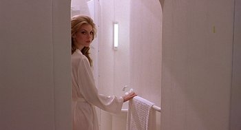 Movie still from “CQ” (2001), directed by Roman Coppola – A woman in a white bathrobe holding a white towel; Medium shot, Low angle