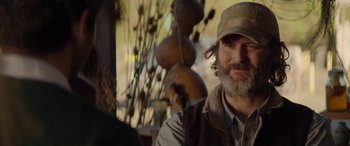 Movie still from “Cabin Fever” (2016), directed by Travis Zariwny – A man with a beard wearing a hat and vest; Close Up shot, Over the shoulder angle