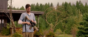 Movie still from “Cabin Fever” (2016), directed by Travis Zariwny – A man is holding an ar - 1 5 and a rifle in his hands; Medium shot, Over the shoulder angle