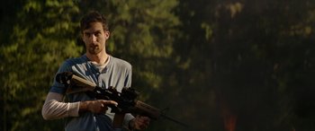 Movie still from “Cabin Fever” (2016), directed by Travis Zariwny – A man holding a rifle in his hands; Medium shot, Low angle