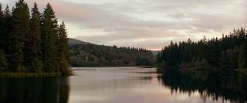 Movie still from “Cabin Fever” (2016), directed by Travis Zariwny – A body of water surrounded by trees and a hill; Extreme Wide shot, High angle