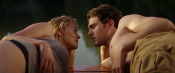 Movie still from “Cabin Fever” (2016), directed by Travis Zariwny – A man and a woman laying on the ground next to a body of water; Medium shot, Low angle