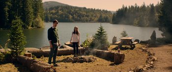 Movie still from “Cabin Fever” (2016), directed by Travis Zariwny – A man and a woman standing in front of a fire pit; Wide shot, Over the shoulder angle