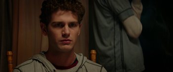 Movie still from “Cabin Fever” (2016), directed by Travis Zariwny – A young man with curly hair and a hoodie; Close Up shot, Over the shoulder angle