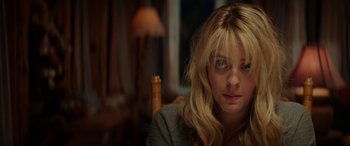 Movie still from “Cabin Fever” (2016), directed by Travis Zariwny – A woman sitting in front of a lamp in a room; Close Up shot, Low angle