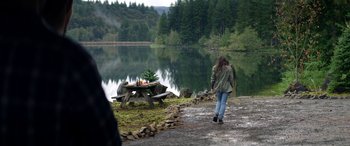 Movie still from “Cabin Fever” (2016), directed by Travis Zariwny – A woman walking down a path near a picnic table; Wide shot, Over the shoulder angle