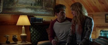 Movie still from “Cabin Fever” (2016), directed by Travis Zariwny – A man and a woman sitting on a couch holding a drink; Medium shot, Over the shoulder angle