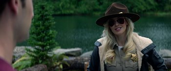 Movie still from “Cabin Fever” (2016), directed by Travis Zariwny – A woman wearing a hat and sunglasses standing next to a body of water; Close Up shot, Over the shoulder angle