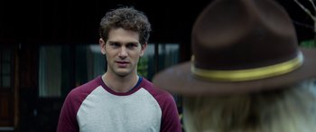 Movie still from “Cabin Fever” (2016), directed by Travis Zariwny – A man in a red and white raglan t - shirt and a brown hat; Close Up shot, Over the shoulder angle