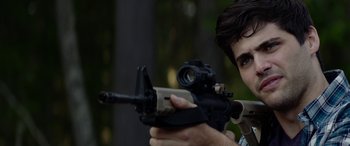 Movie still from “Cabin Fever” (2016), directed by Travis Zariwny – A man holding a rifle and aiming it with a rifle sight; Close Up shot, Over the shoulder angle