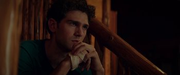 Movie still from “Cabin Fever” (2016), directed by Travis Zariwny – A young man sitting on the steps of a house; Close Up shot, Low angle