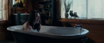 Movie still from “Cabin Fever” (2016), directed by Travis Zariwny – A woman sitting in a bath tub next to a window; Medium shot, Over the shoulder angle