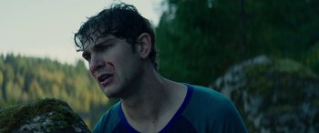 Movie still from “Cabin Fever” (2016), directed by Travis Zariwny – A man with a bleeding face and a green shirt; Close Up shot, Over the shoulder angle