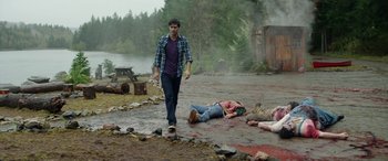 Movie still from “Cabin Fever” (2016), directed by Travis Zariwny – A man walking down a road next to dead bodies; Wide shot, Over the shoulder angle