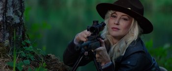 Movie still from “Cabin Fever” (2016), directed by Travis Zariwny – A woman in a hat is holding a rifle; Close Up shot, Over the shoulder angle